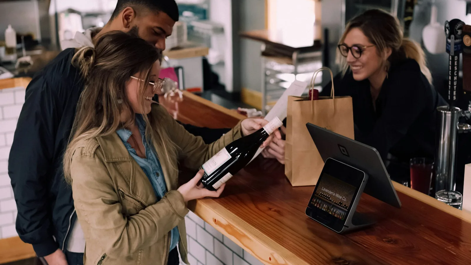 Main présentant une carte de fidélité digitale moderne dans un commerce de proximité, ambiance chaude.