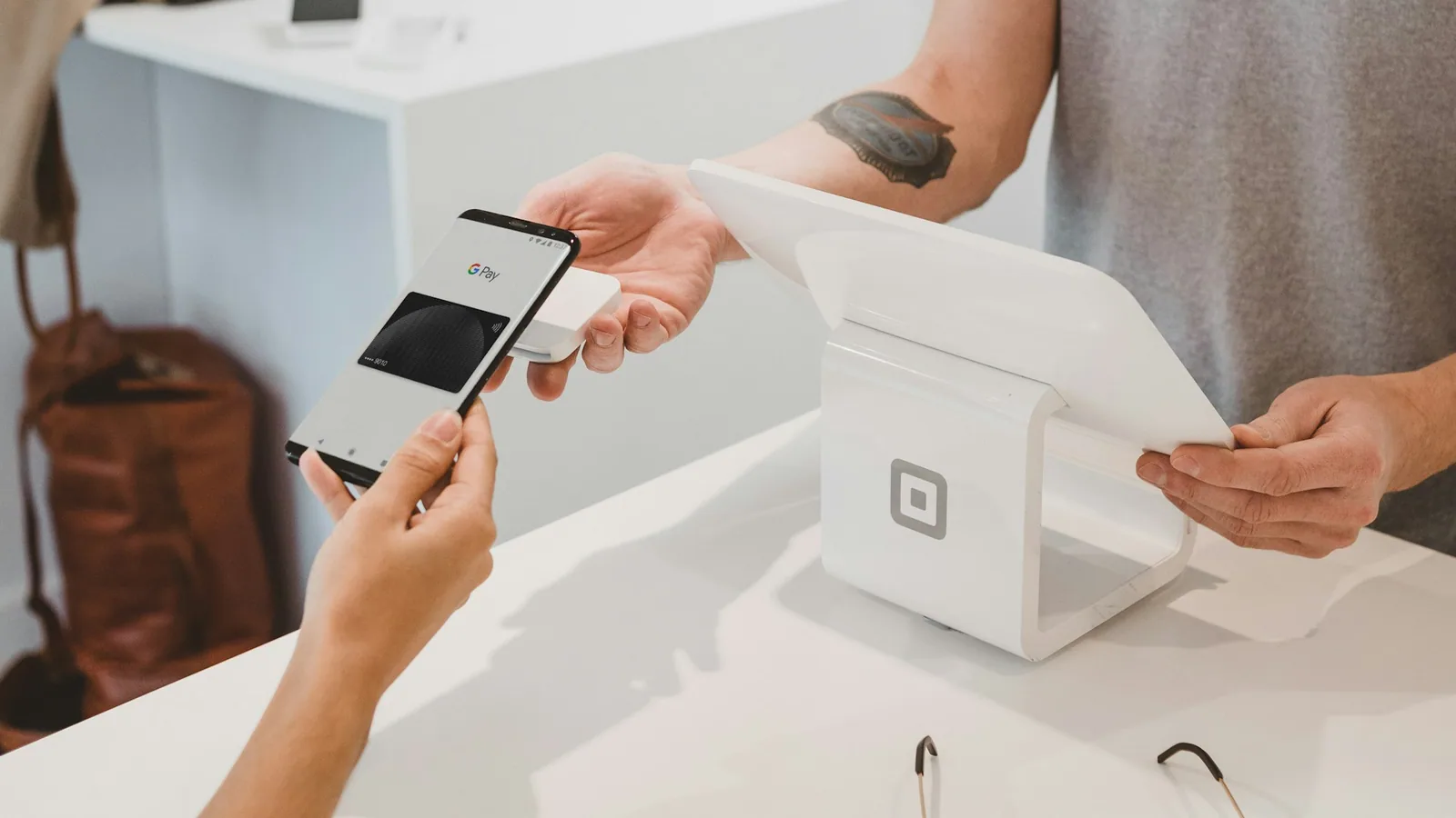 Cliente scannant son smartphone à l'accueil d'un institut de beauté chaleureux, bougies et produits cosmétiques en arrière-plan.