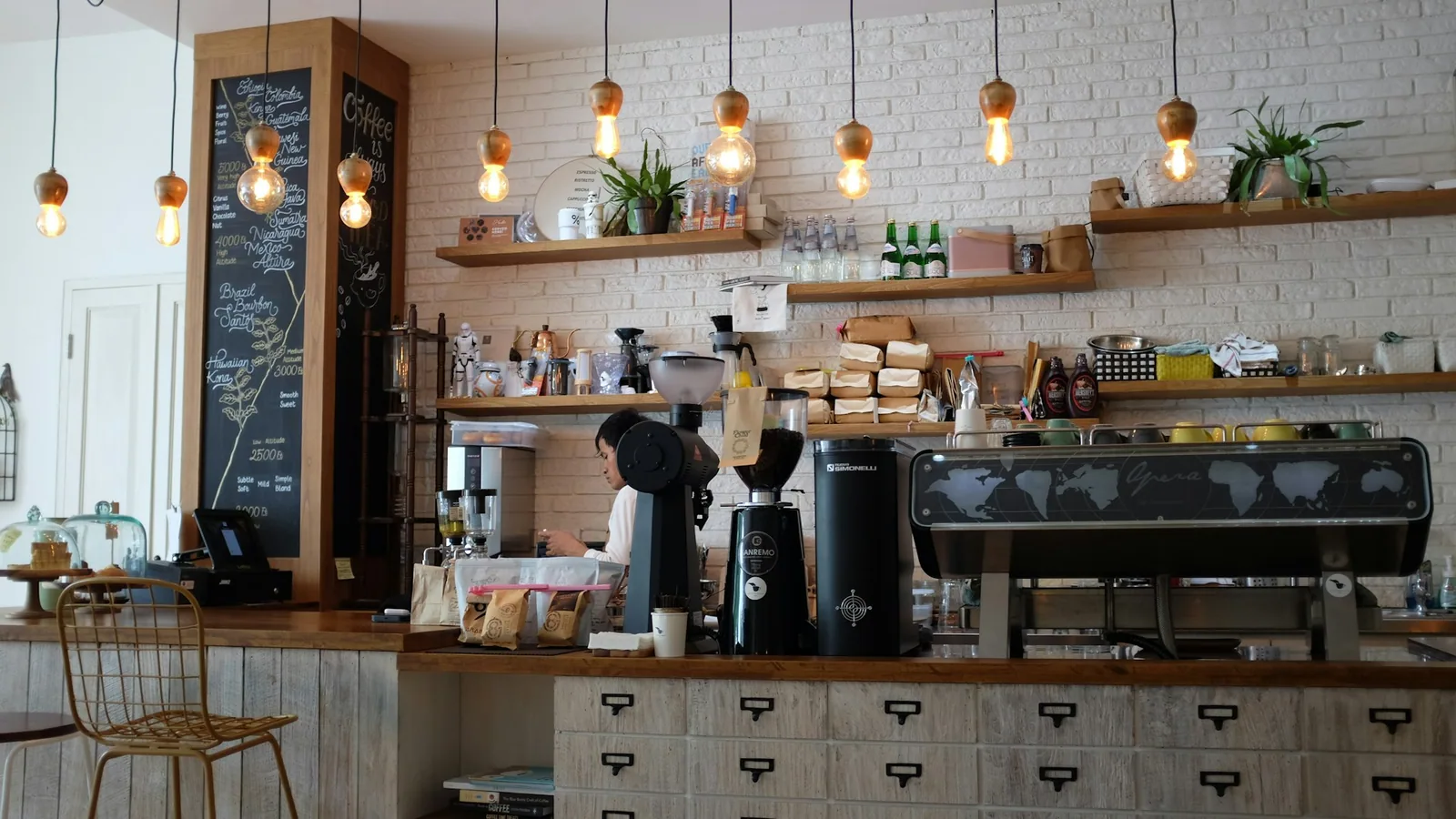 Sac de café en grains posé sur un comptoir en bois, latte art au premier plan, lumière douce d'un café-torréfacteur indépendant.