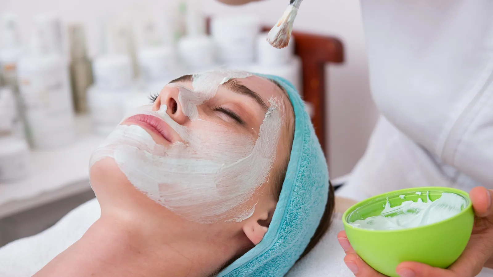 Cabine de soins chaleureuse d'institut de beauté, bougie allumée, serviettes en lin, lumière tamisée.
